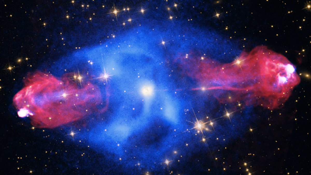 This is an image of Cygnus A in X-ray, optical, and radio light. A giant blue, elliptical bubble of gas (X-rays) surrounds a bright white X-ray source. Jets shooting outward from both the left and right of the bubble are seen in radio (red) and they extend more than 300,000 light years in each direction.