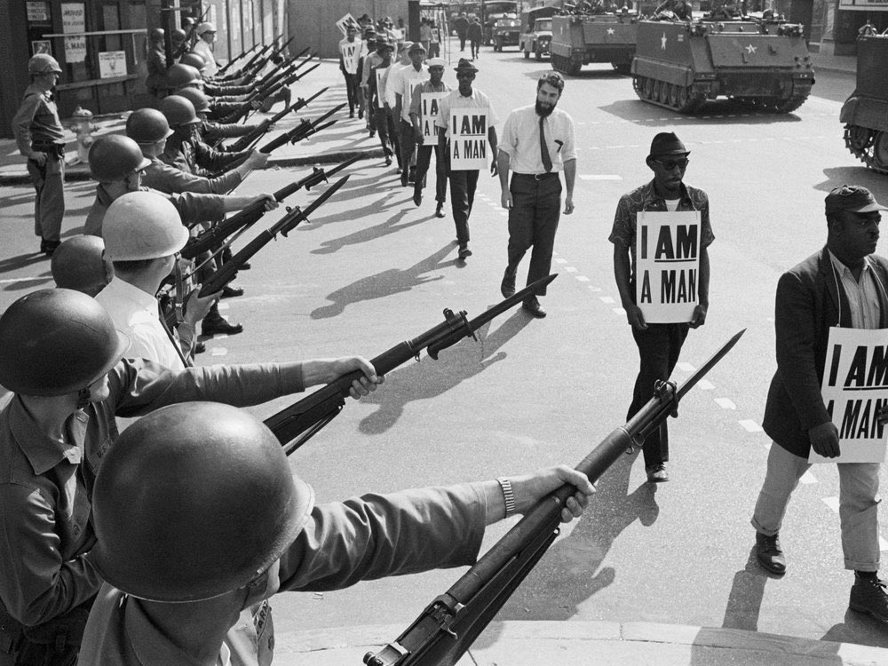 National Guard troops lined Beale Street during a protest by Memphis Sanitation Workers on March 29 , 1968. They are holding signs saying I Am A Man