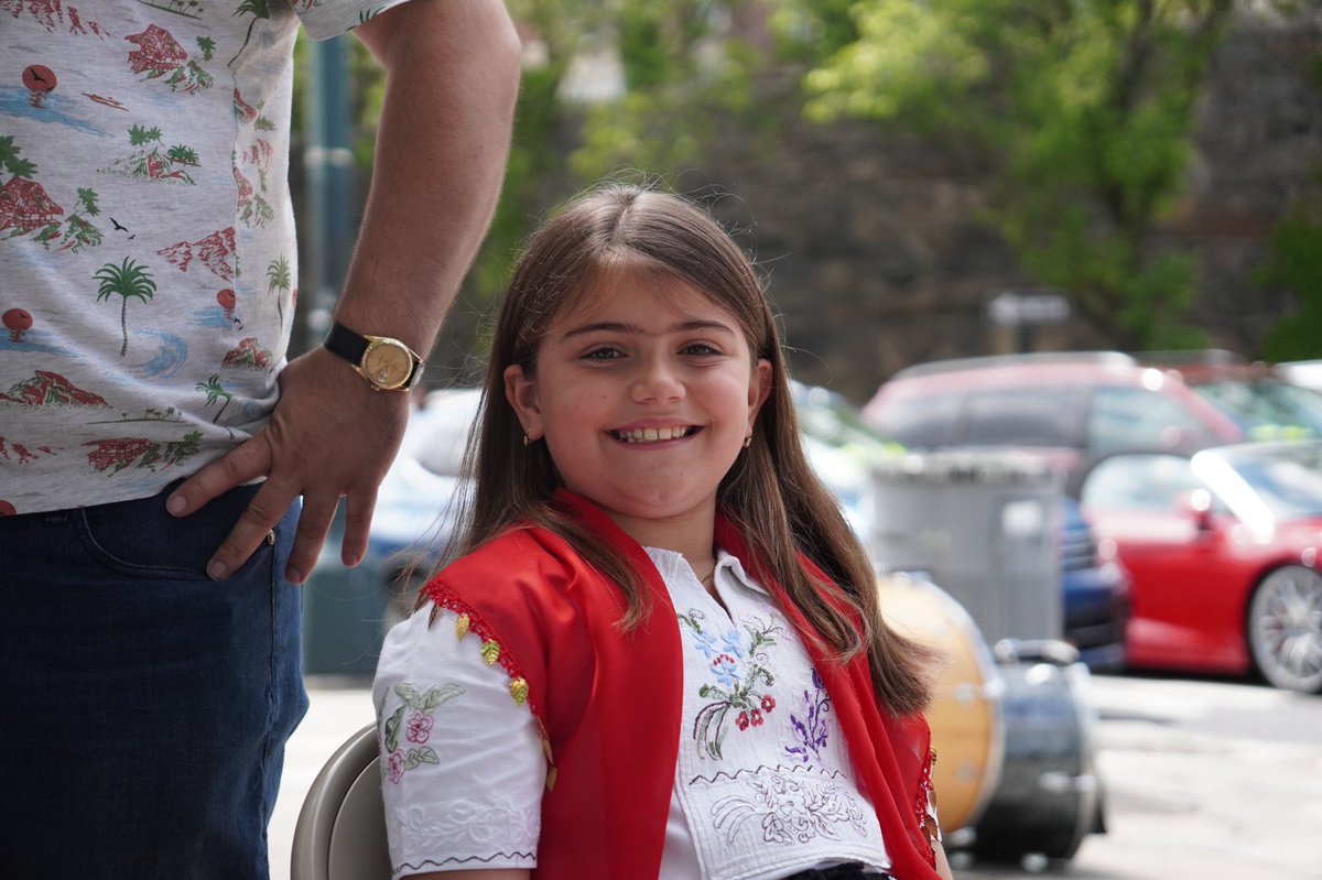 A young girl smiles for the camera. She is wearing traditional Albanian