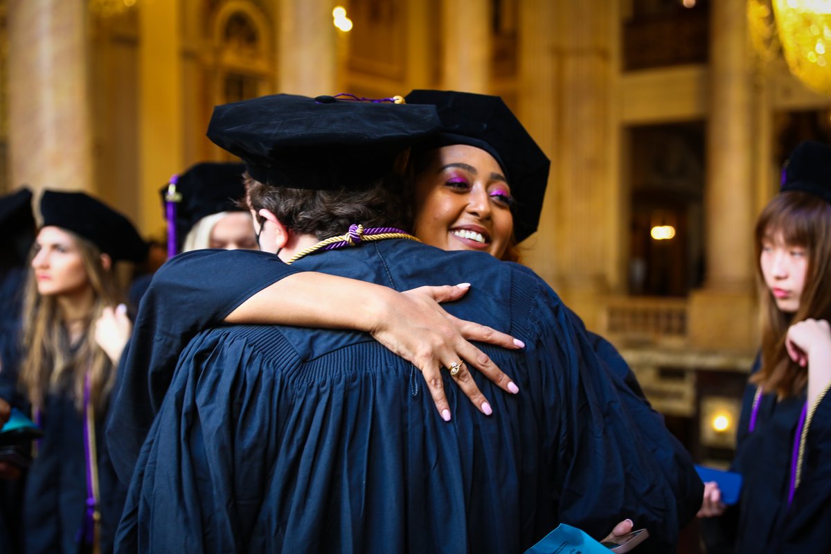 two 2020 graduates hug each other inside the chicago theatre
