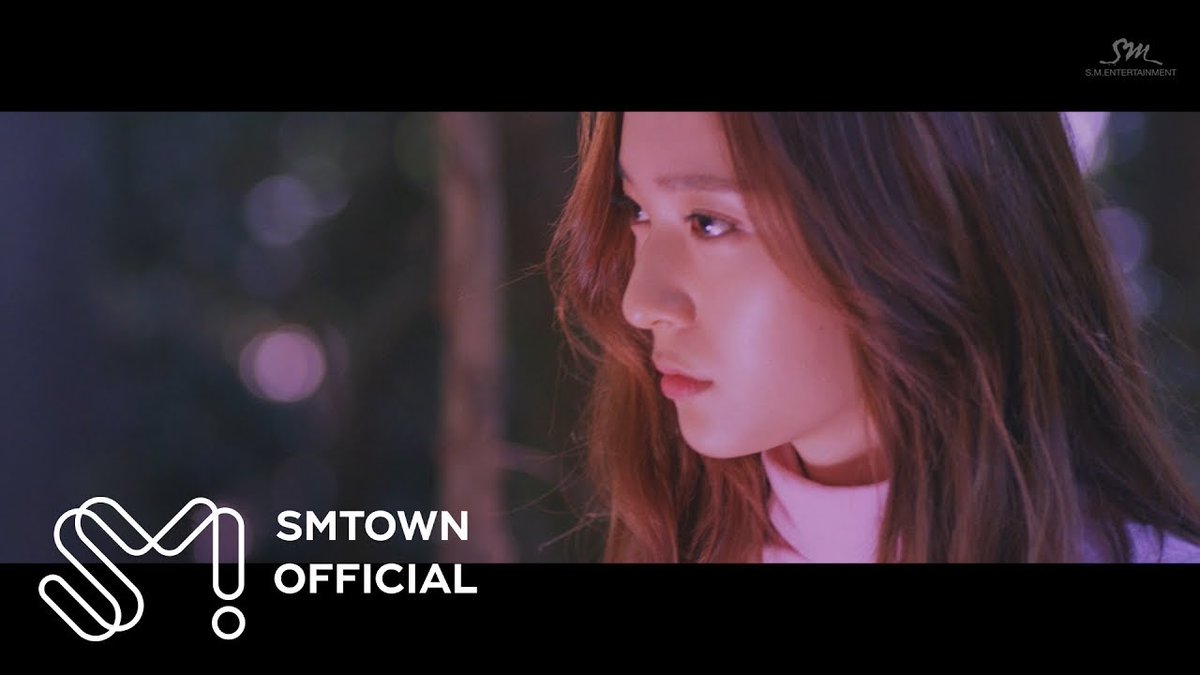 A profile shot of a woman with long brown hair in a pink-lit scene, branded with 'SMTOWN OFFICIAL' and 'S.M. ENTERTAINMENT' watermarks.