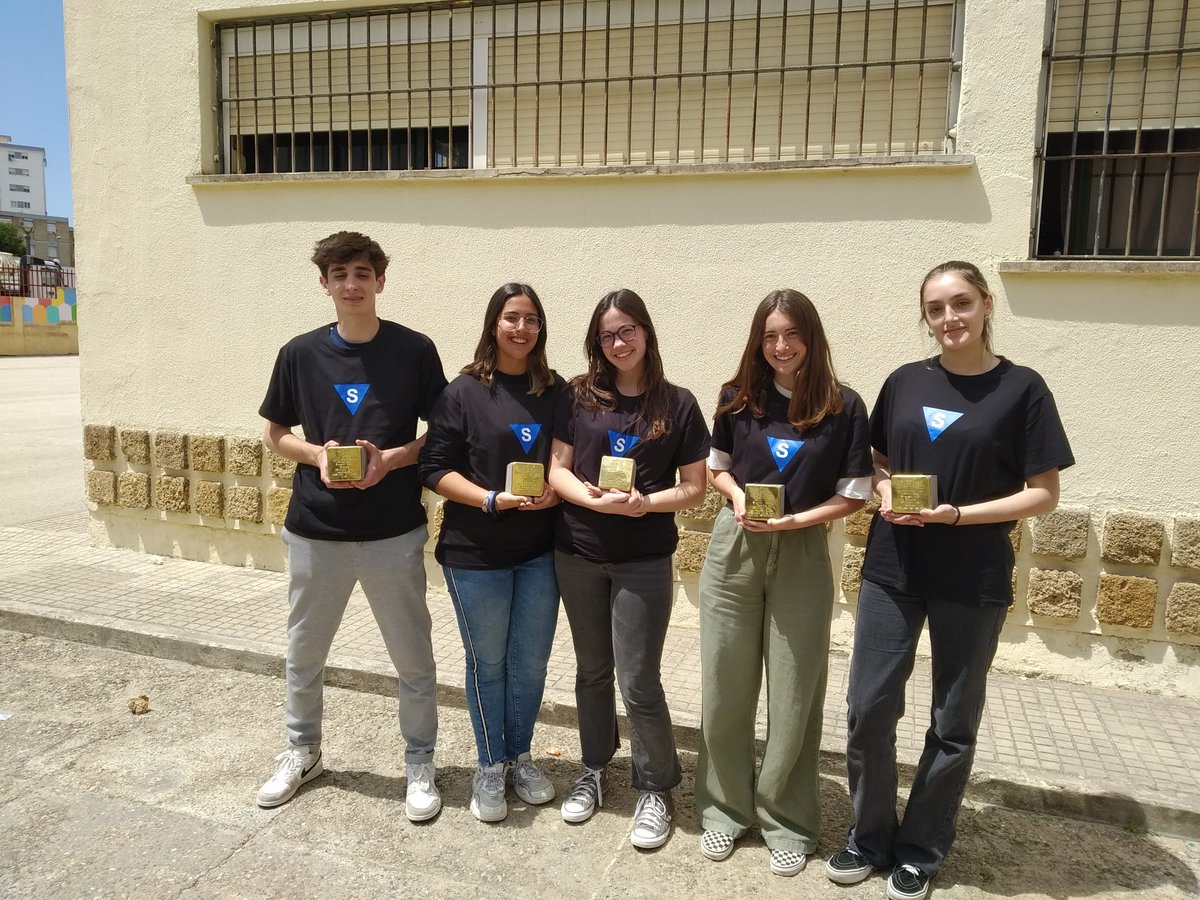 StolpersteineJ's tweet photo. En las imágenes podemos ver a algunos alumnos y alumnas de segundo de Bachillerato, con camisetas con el triángulo azul de los "Rotspanier", los deportados españoles a campos de concentración y exterminio nazis. https://t.co/sMfDoeiRoL