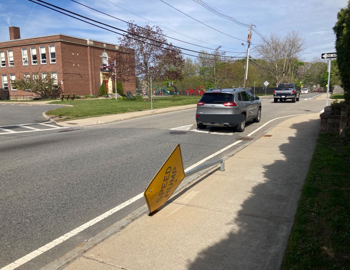 DedhamByFoot's tweet photo. Another day on #NeedhamSt, another sign knocked over.  Cars continue to gleefully stream over the #SpeedHump that already does very little to slow drivers, right at the pedestrian crossing that also has no signs, literally at @DedhamRiverdale #DedhamMA @DedhamThrives https://t.co/wyA96l7S8r