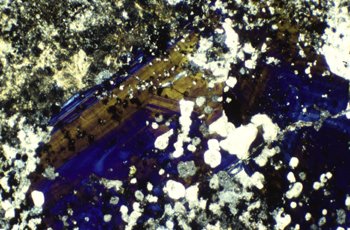CardiffCurator's tweet photo. Like an abstract painting #SciArt 

#vesuvianite is typical of contact metamorphism of impure limestones/skarns. In thin section, identified by Berlin blue colours under x polarised light. Here: zoned crystal with calcite, Anglesey View: 2.5mm 

#A_Z_WelshMinerals #MineralMonday https://t.co/KrWFFDz8l9