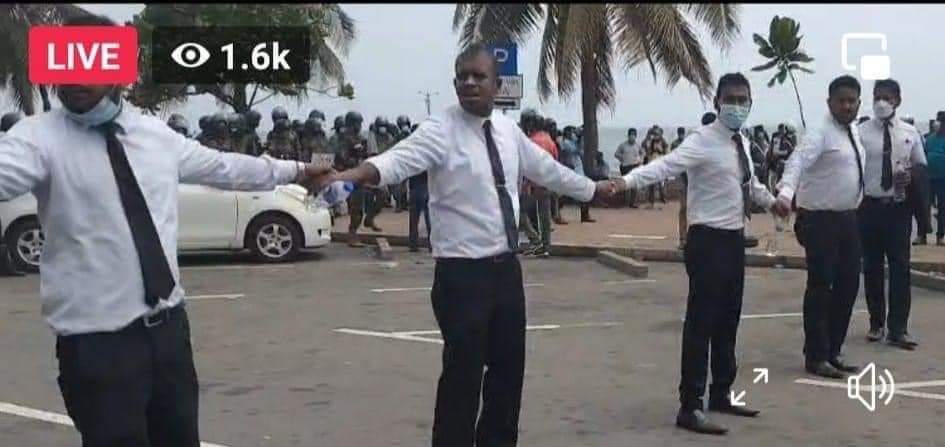 Nawfan1234's tweet photo. Livestreams show lawyers forming a human barrier to protect peaceful protesters at #GotaGoGama. Throughout the 71 continuous days of protests in #SriLanka demanding the resignation of the President and government, lawyers have shown up in numbers to defend protesters in court. https://t.co/OL98jUXQPt
