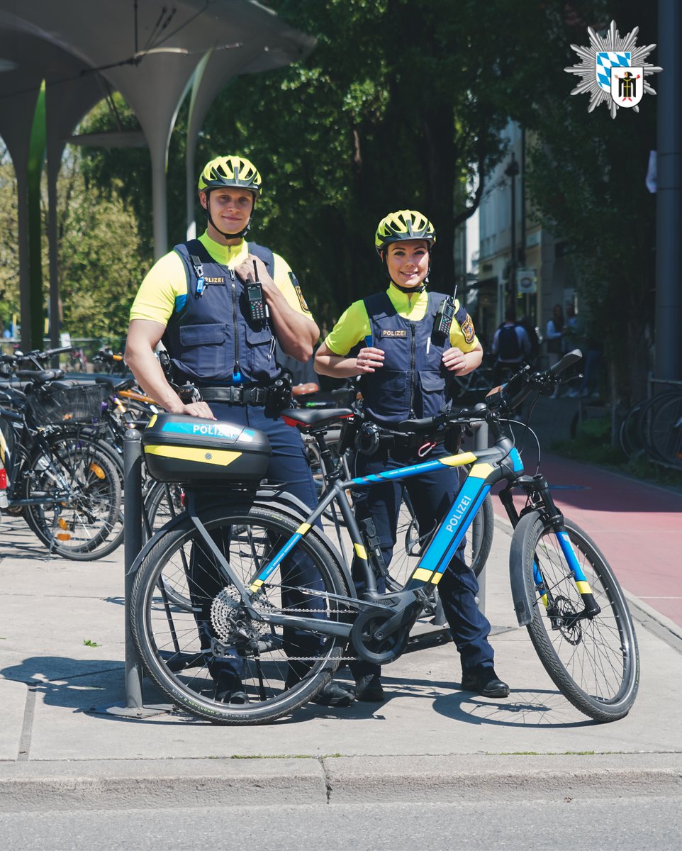 Eine Polizistin und ein Polizist stehen Fahrradstreife vor der Münchner Freiheit.