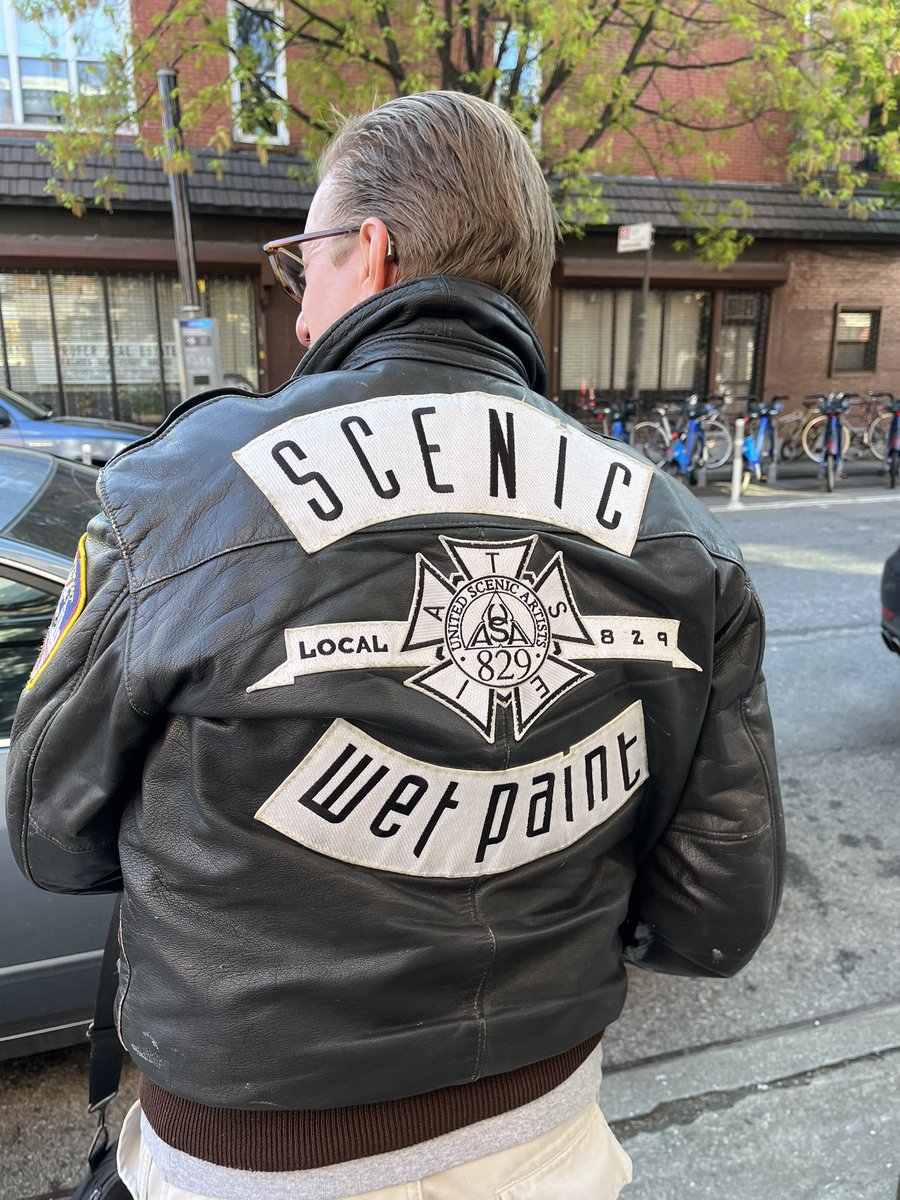 back of a black leather jackets that says scenic wet paint. In the middle is a local 829 IATSE emblem.