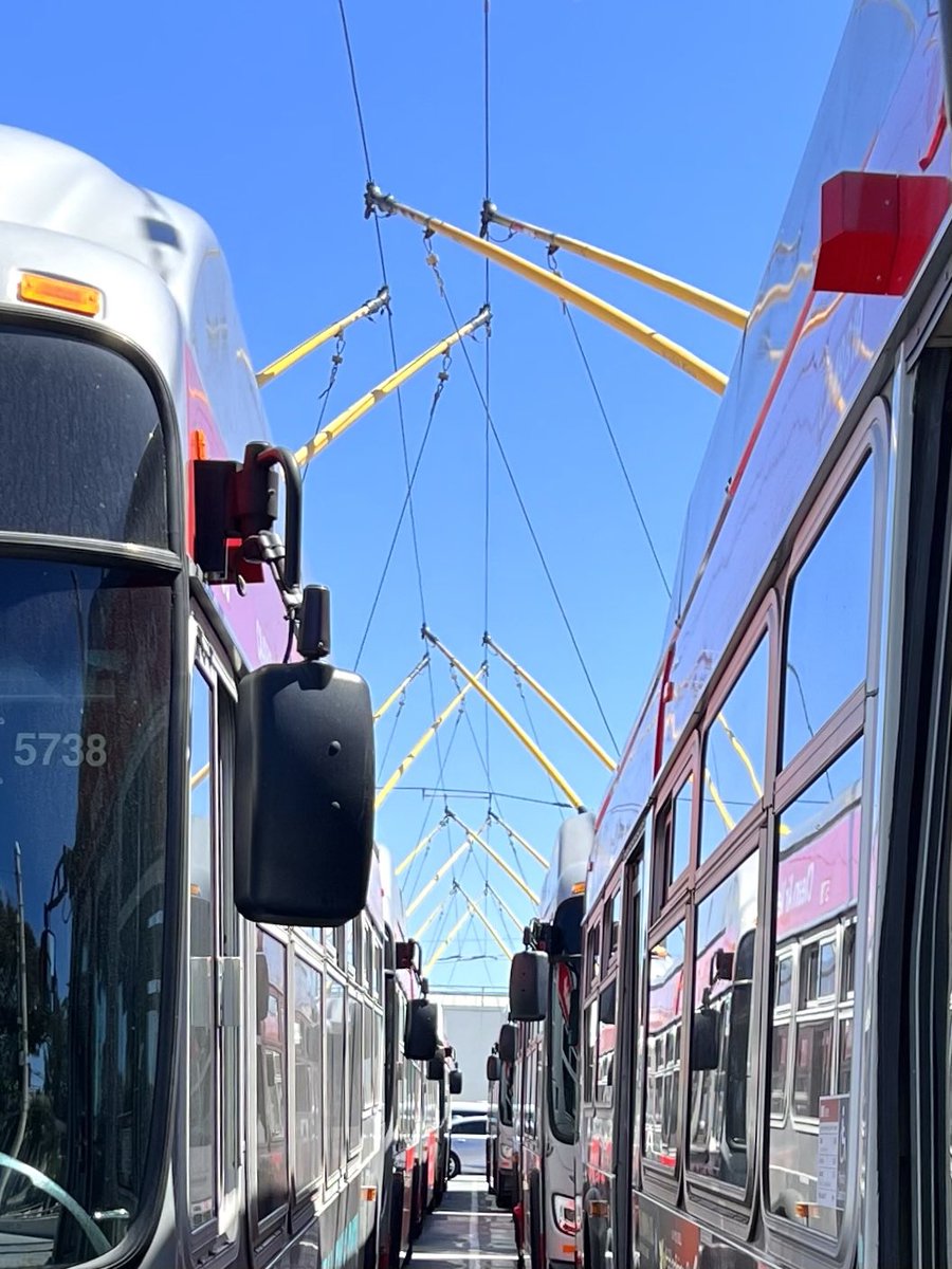 Two parallel lines of parked trolleybuses with their trolley poles criss-crossed in pairs overhead
