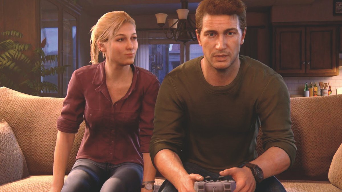 Nathan and Elena sit together on the couch. Nathan holds a PlayStation DualShock controller. 