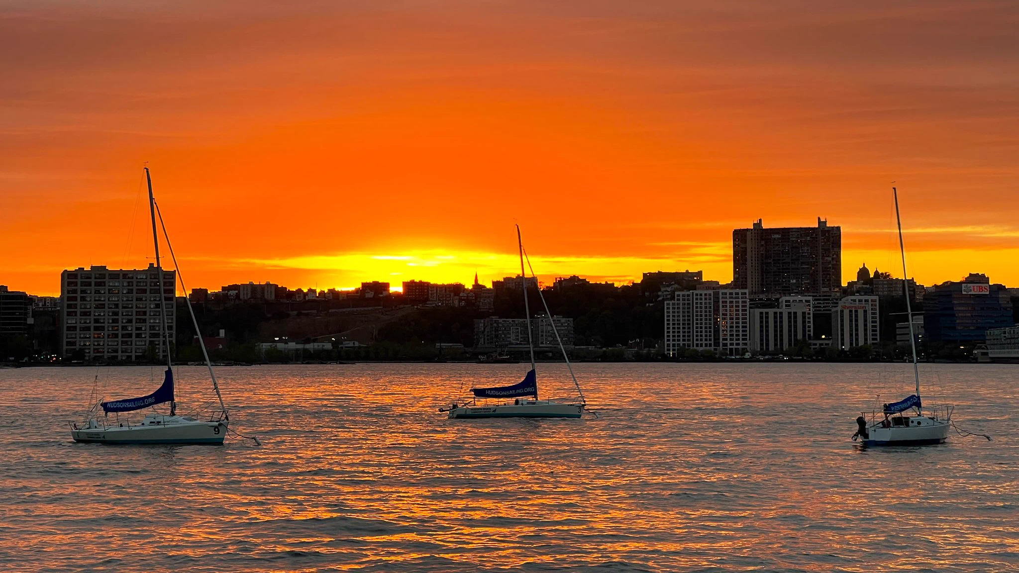 Sailboats moored on the Hudson River with the sunset behind them