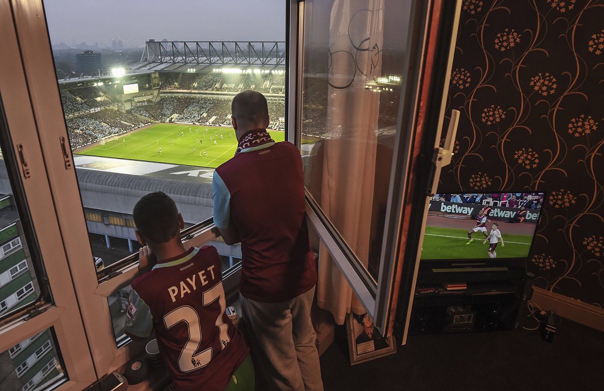 LowerBlock's tweet photo. @MichaelRegan wins Highly Commended in @BarclaysFooty &amp; @FPA_2020 ‘Shot of the Century’ photo comp for his poignant image of a young fan and his father watching from their window as West Ham United play their last ever match at Upton Park. #westham #uptonpark #footballfans https://t.co/XU8qI5R4Sb