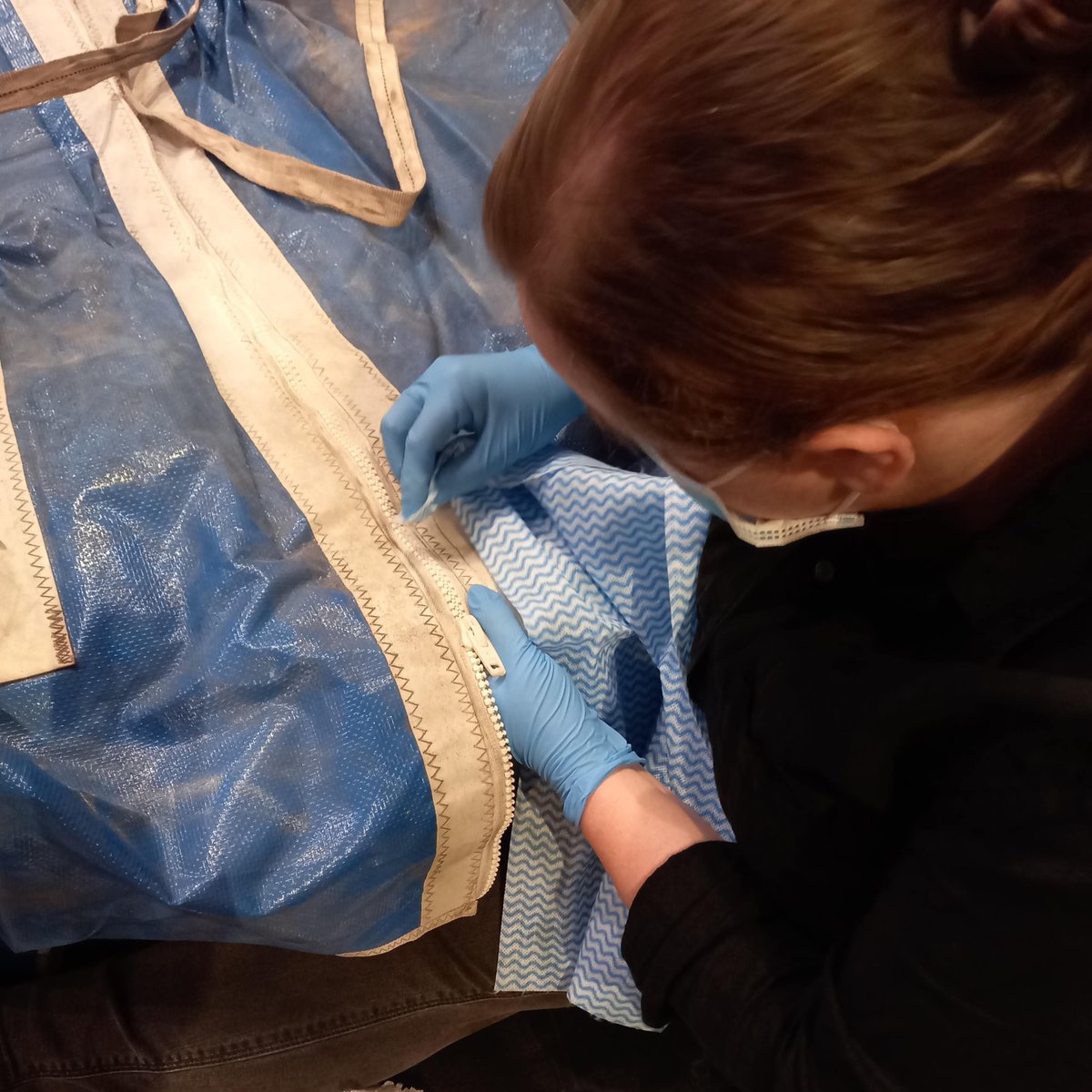 nz_maritime's tweet photo. After 30+ years in storage, it’s no surprise that some of the #KZ1 sails require extra care as they're unpacked for #NZMMDigitisation. This sail bag's zip was fused together with salt build-up. Careful cleaning means the sail can be safely accessed without damage to the bag. https://t.co/4yEZZrOR8d