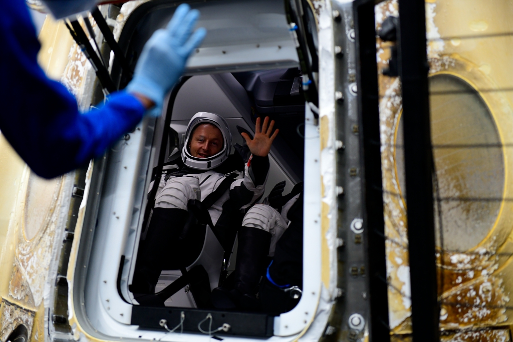 ESA astronaut Matthias Maurer pictured through the door of Crew Dragon capsule Endurance. He is waving and wearing his SpaceX flight suit. 