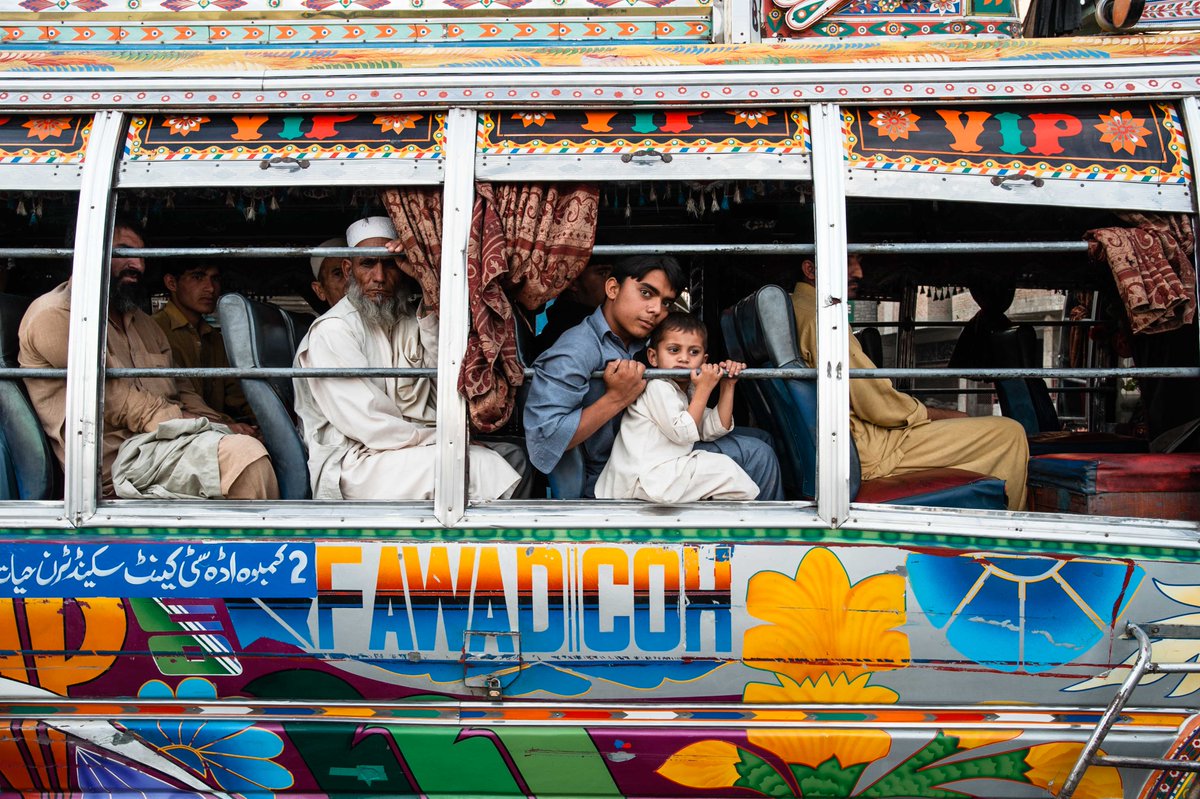 alissaeverett's tweet photo. Heading Home. #Peshawar, #Pakistan. A young man and his little brother caught my eye, peering out the bus, painted beautifully, color in a city of cement. This image features in my show, COVERING BEAUTY, in Venice.  #personalstructures https://t.co/jKN1zfZqgC