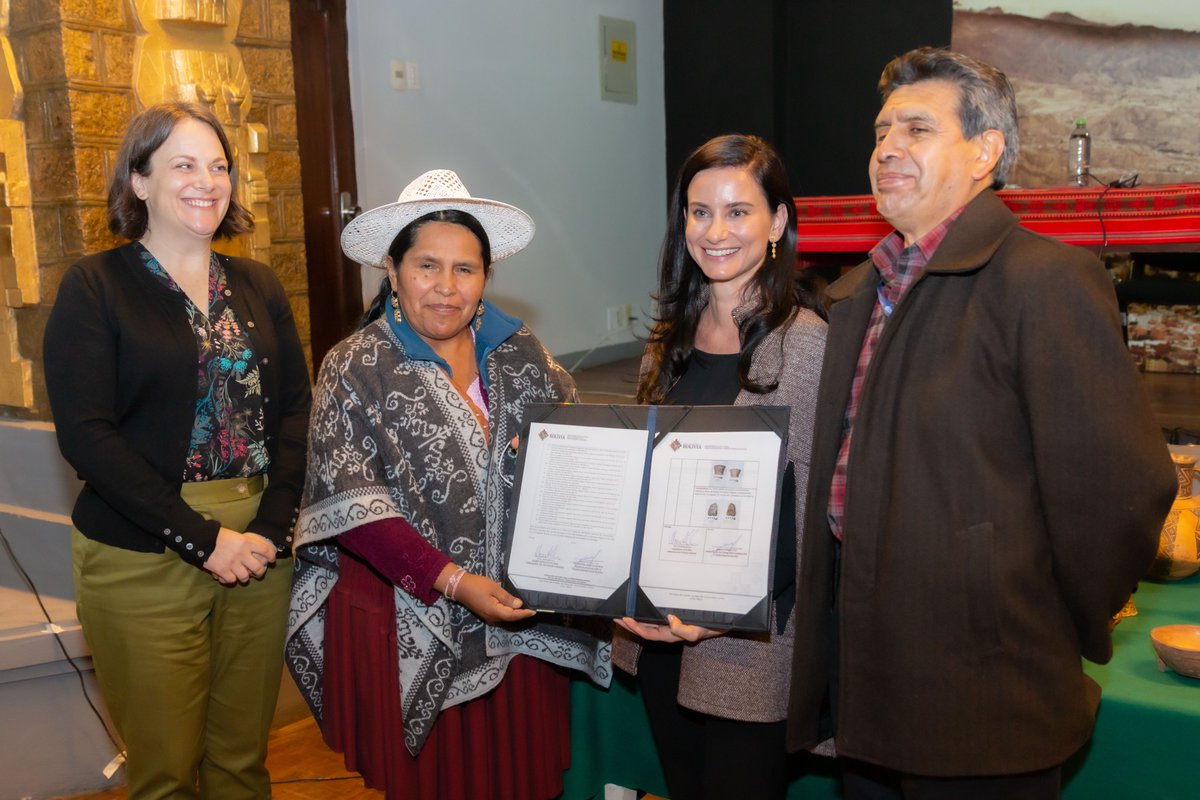 Four people pose for a photo, with the two in the middle both holding an opened folio.