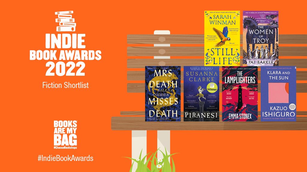 An orange graphic promoting the Fiction Shortlist for the Indie Book Awards 2022. The logo has five stacked books and the text “Indie Book Awards 2022”. There is a bench with six Fiction book jackets and grass and daisies underneath.