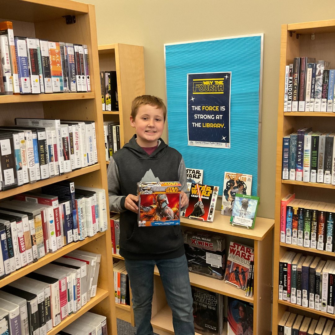 You boy holding a Star Wars puzzle - in a library setting.