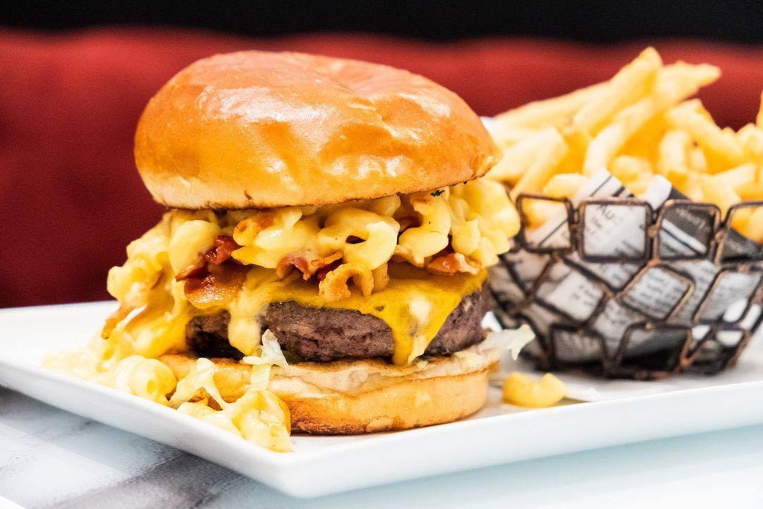 Our famous Big Cheesy Burger! 🍔 8 oz black angus beef, topped with melted American cheese, creamy mac & cheese, applewood smoked bacon, pickles, shredded lettuce, tomatoes, crispy onions and BBQ sauce on a brioche bun! #SanDiego #TheatreBoxSD #SugarFactory