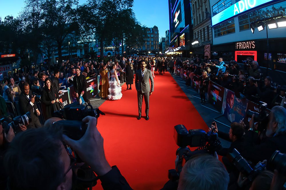 Photographers point their cameras at people on a red carpet