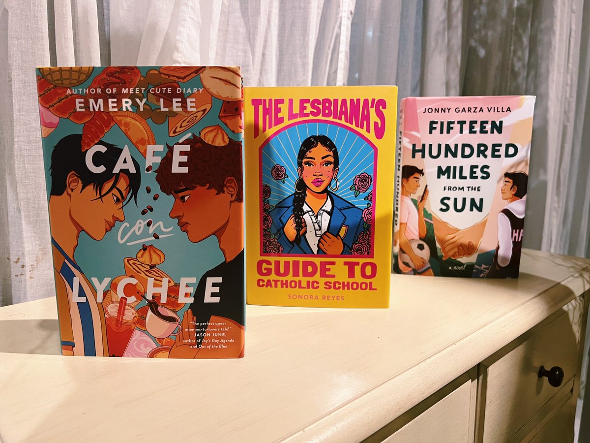 Café Con Lychee by Emery Lee, The Lesbiana’s Guide to Catholic School by Sonora Reyes, and Fifteen Hundred Miles from the Sun by Jonny Garza Villa on a dresser in Ripped Bodice, an indie bookstore in Los Angeles, California.