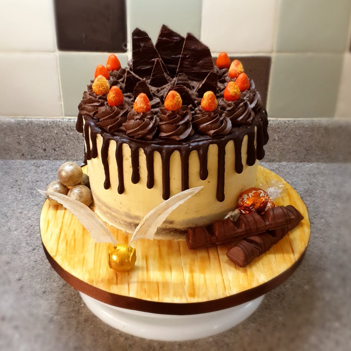 AlexExile10's tweet photo. In case anyone missed my retweet yesterday, here's a Chocolate Drip Cake I did, with some Lindt Chocolate Orange Truffles, using one to make a Golden Snitch for a Harry Potter fan #ChocolateSponge https://t.co/oNdWyqzIMq