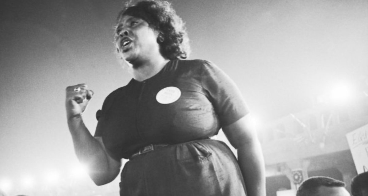 A black and white image of civil rights activist Fannie Lou Hamer standing above a crowd of people.