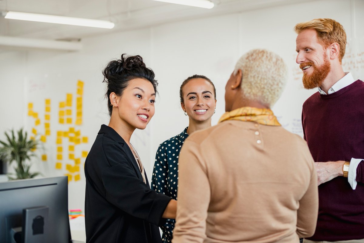 Group of people of mixed ages standing and talking in a meeting room