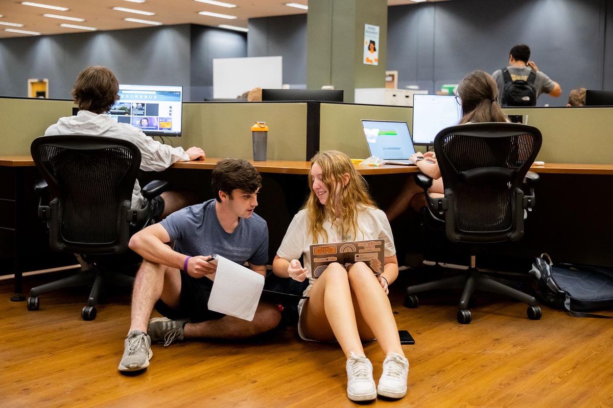Two students sitting in the floor studying in the library