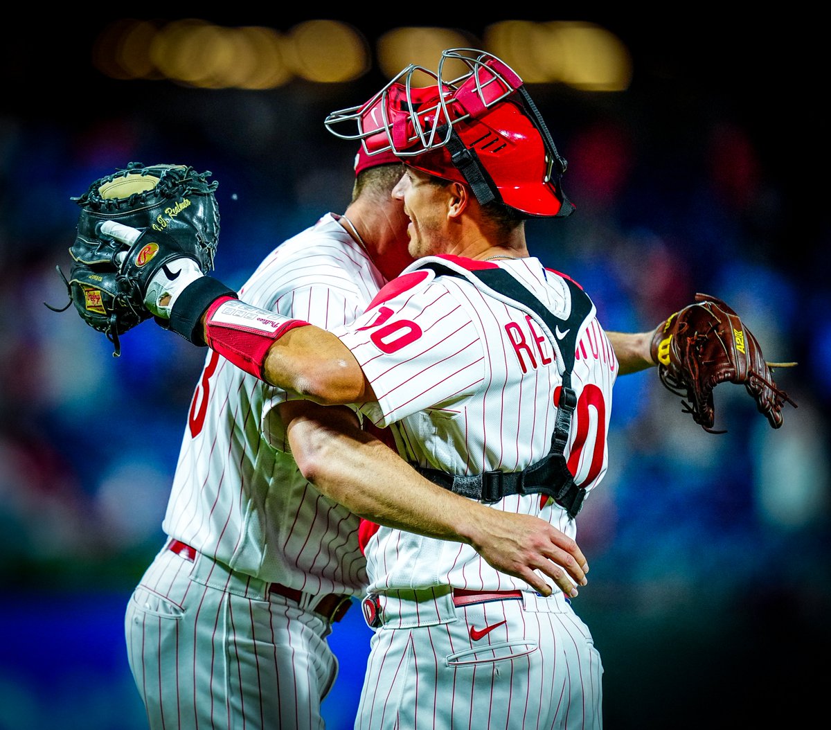 Corey Knebel and J.T. Realmuto, wearing the red pinstripe uniform, hugging after the Phillies win the game.