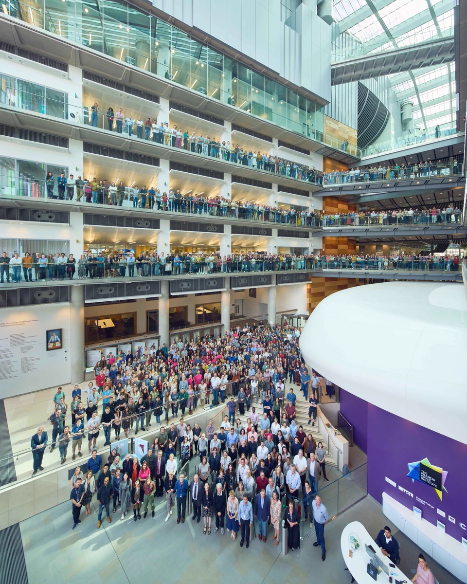 A group picture with hundreds of Crick employees in the front entrance to the building.