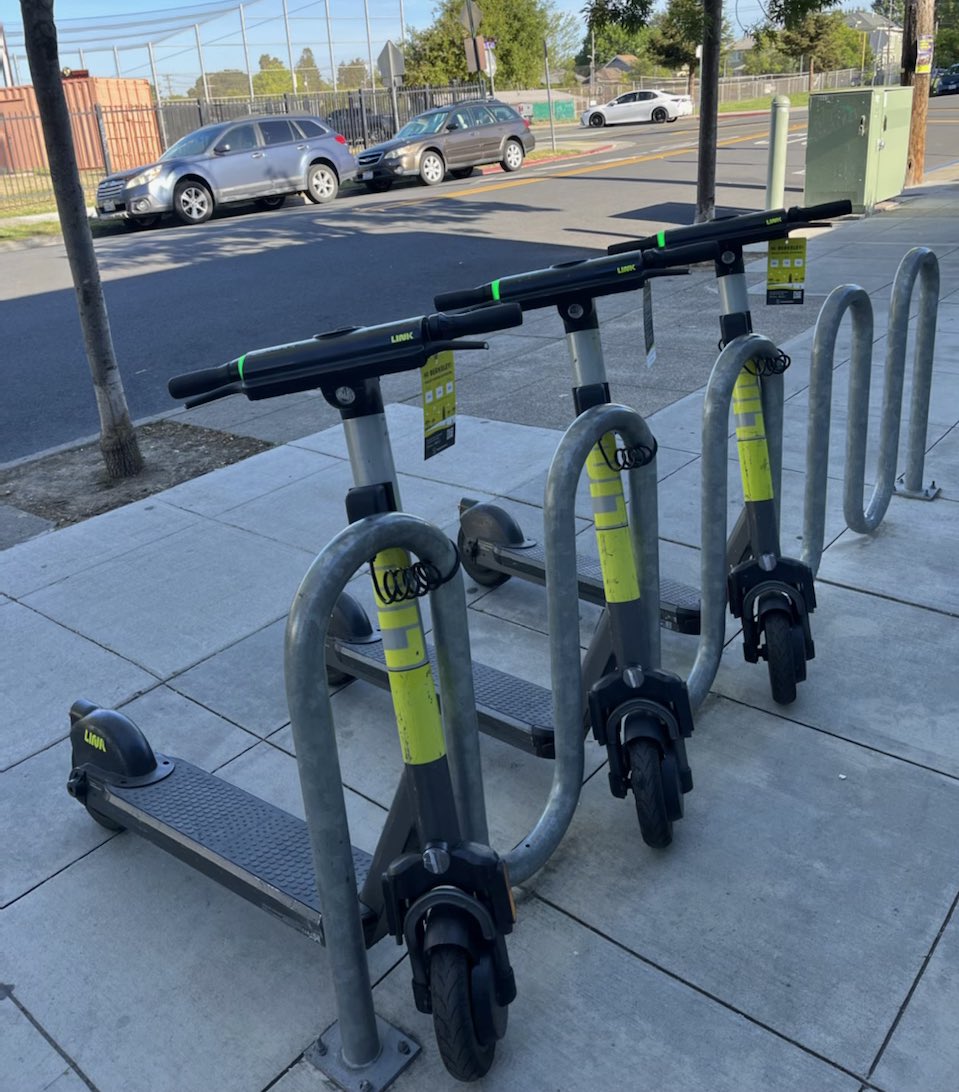 Three electric scooters locked to bike rack