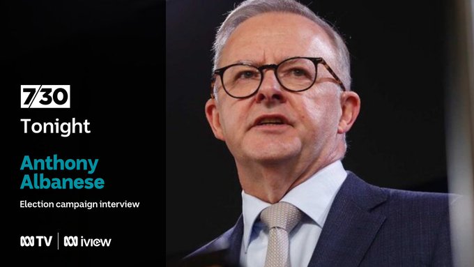 Anthony Albanese wearing a blue suit, pale green tie and dark-framed glasses.