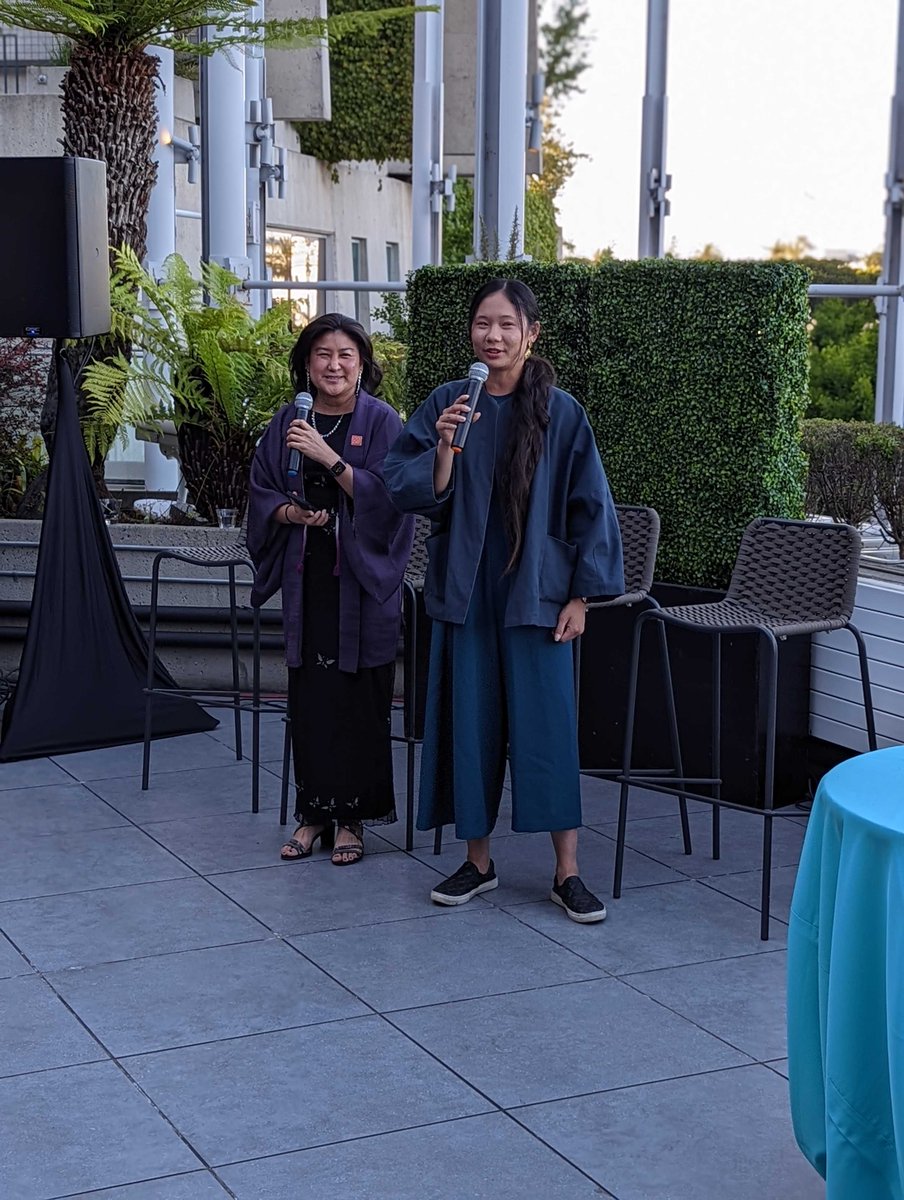 Two Asian women standing outside holding microphones.