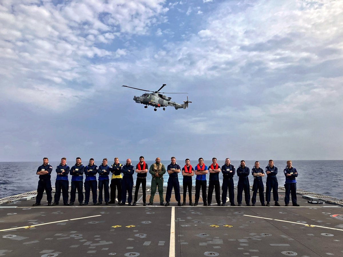 Group shot of the team with the Wildcat off the stern of HMS Trent