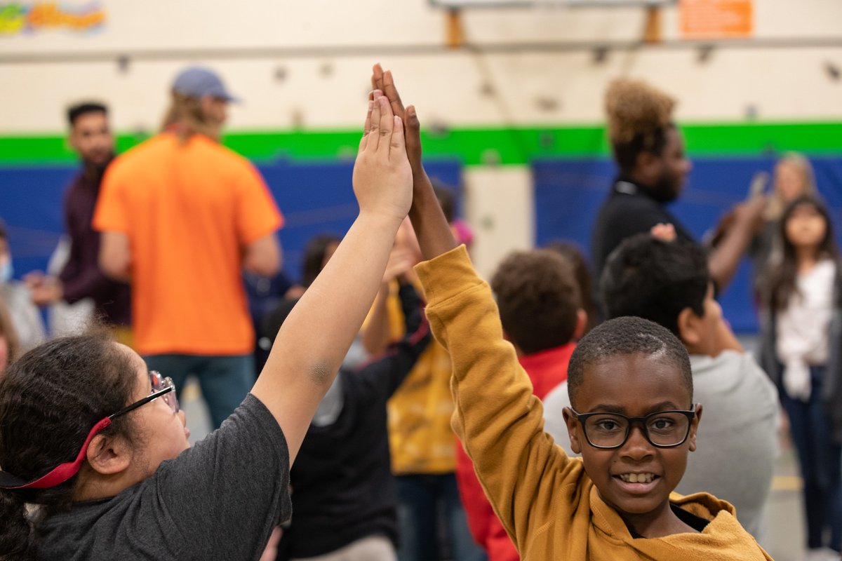 Two students in foreground giving each other a high five.