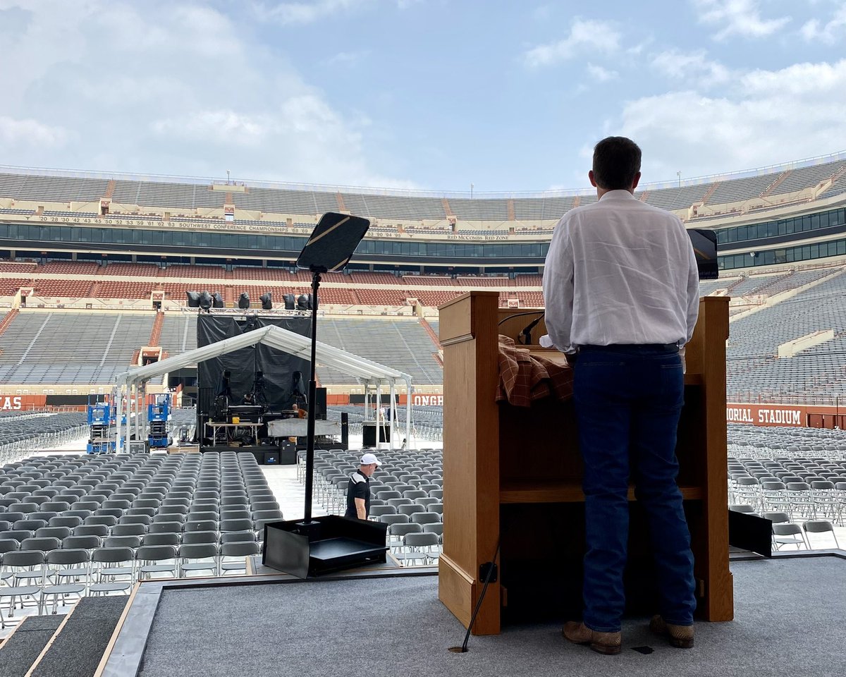 President Hartzell stands at a podium on a stage in DKR-TMS during a rehearsal for Commencement.