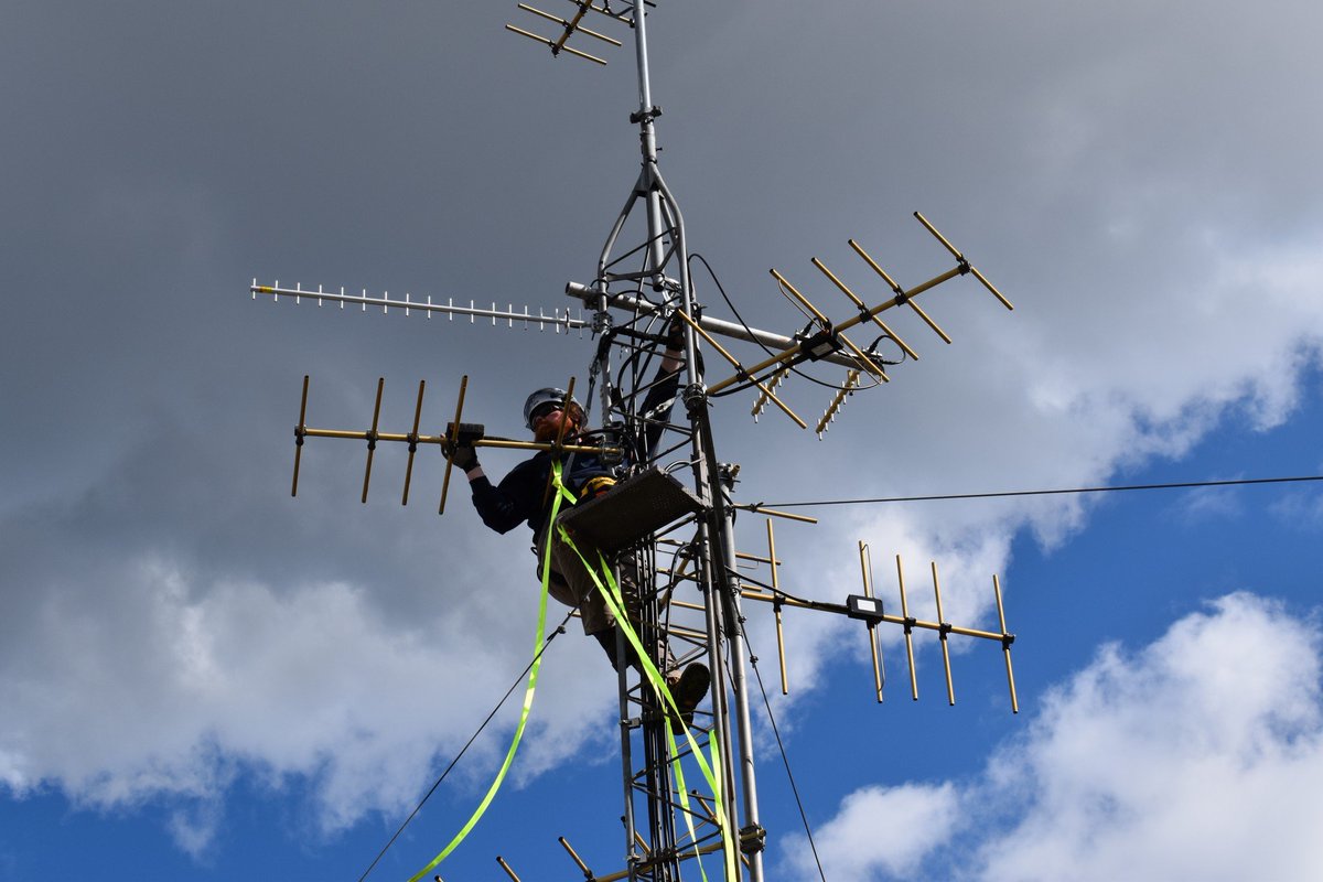 A PNSN field tech hangs off the top of the tower on the ATG roof as he installs a new antenna to join a handful of others.