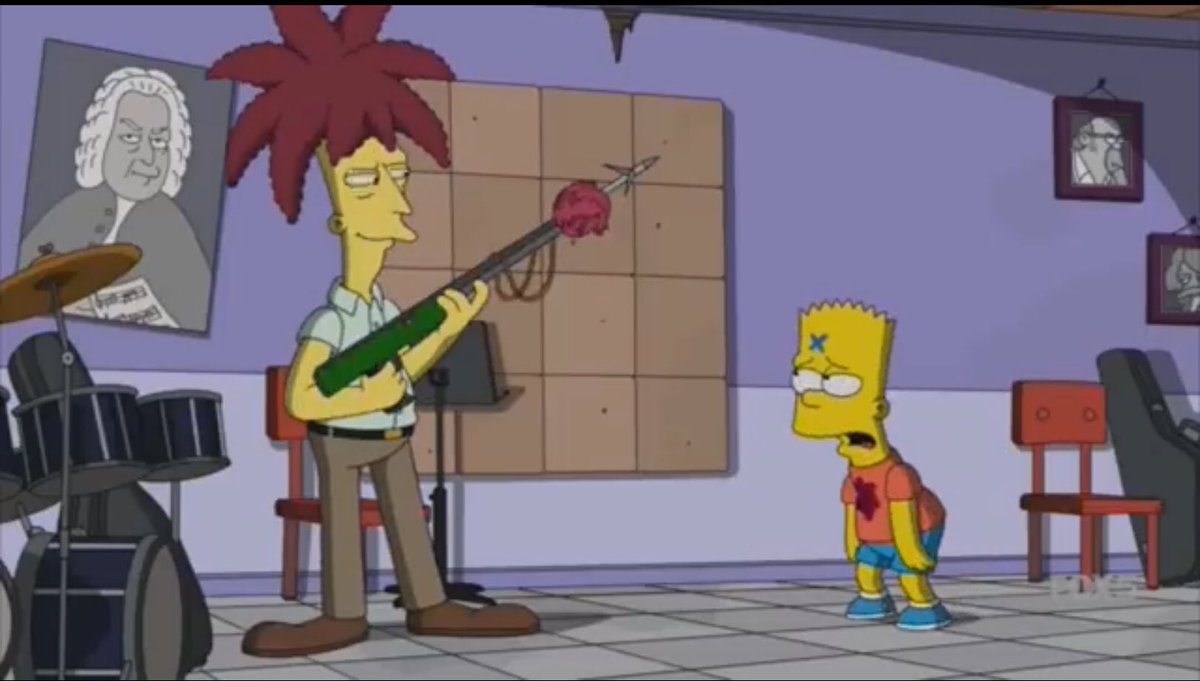 Sideshow Bob from the show “The Simpsons” is seen with a harpoon gun with a bloody heart on the end with Bart Simpsons right next to him with a bloody stain on his shirt looking woozy.
