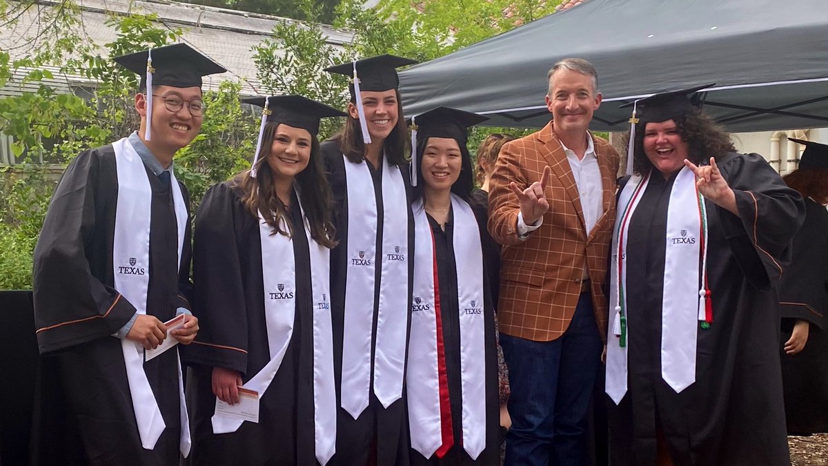 Wearing caps and gowns, five graduates pose for a picture with President Hartzell.