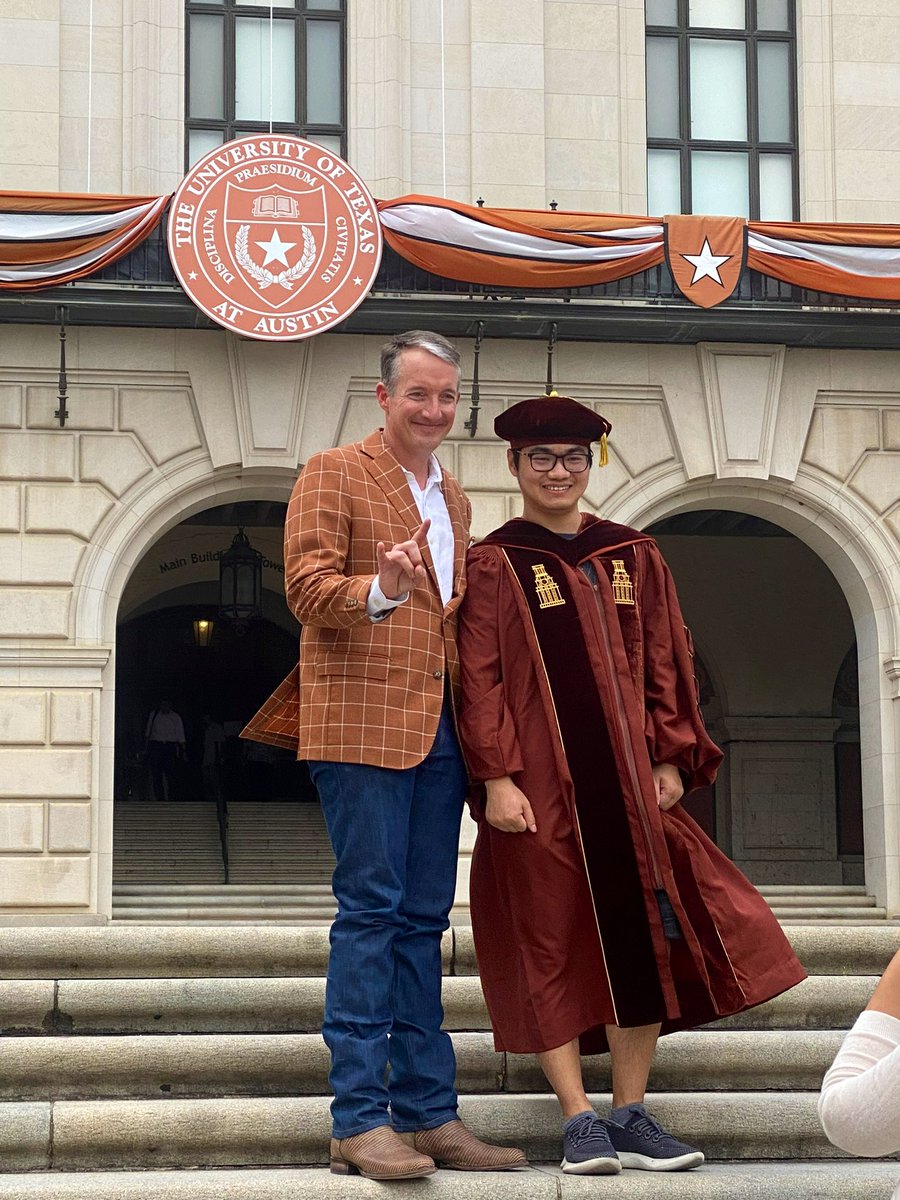 A graduate wearing a cap and gown poses for a picture with President Hartzell.