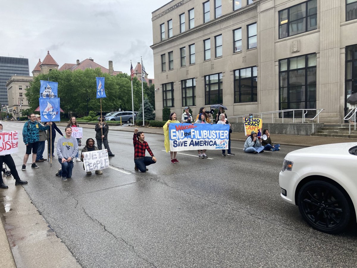 kai_newkirk's tweet photo. BREAKING: West Virginians are risking arrest shutting down street at Robert Byrd federal court house in Charleston. We say, "No more!" to Manchin’s corrupt obstruction! It’s time to end the filibuster and pass legislation to solve the crises facing our nation. #SitInToSaveAmerica https://t.co/BXYy5eFj1s