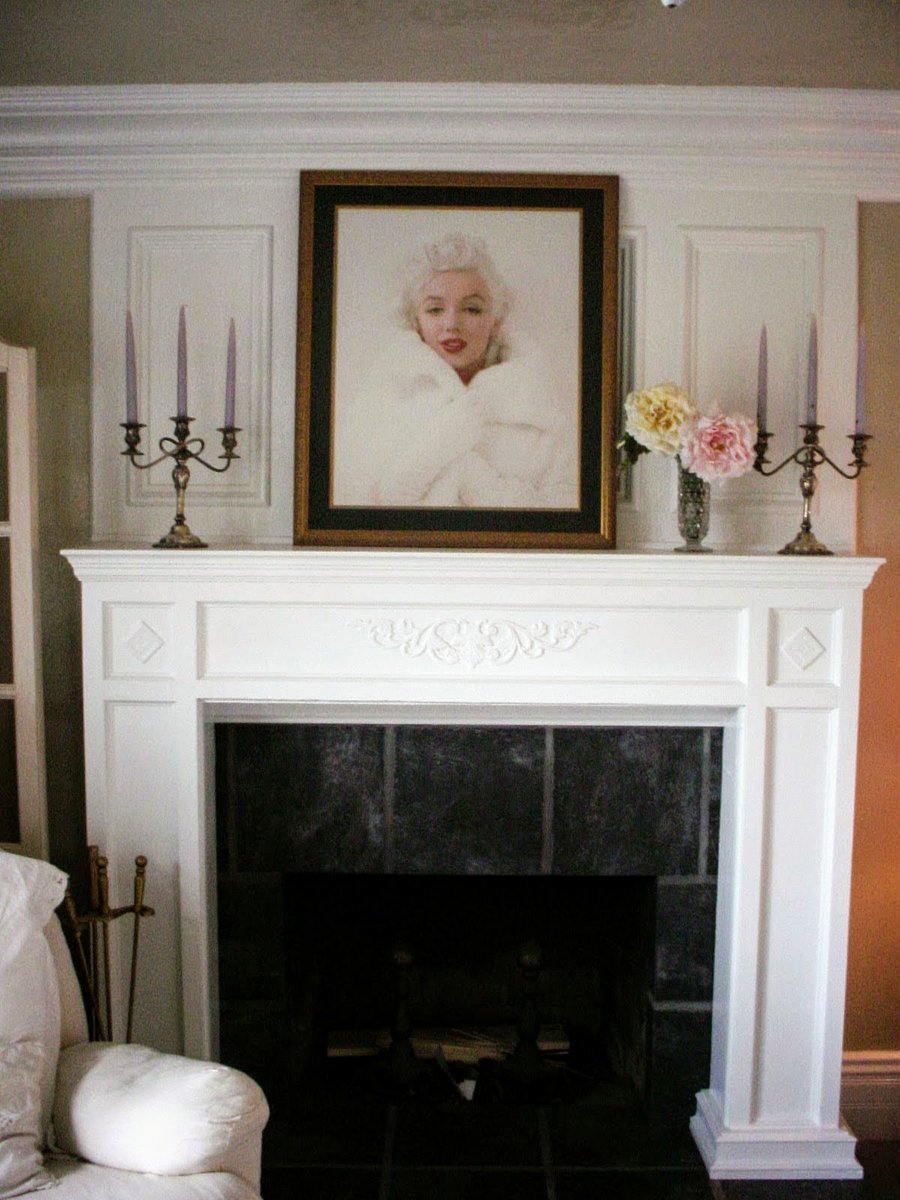 This is how to cover, not demolish a d rebuild
Cover the old red brick fireplace with slate fronts; MDF molding; and real oak trim and panelling.
Don't  need to replace or cover the fire brick.
Thick straight mantle and paint.  Project built to accommodate that Marilyn picture.