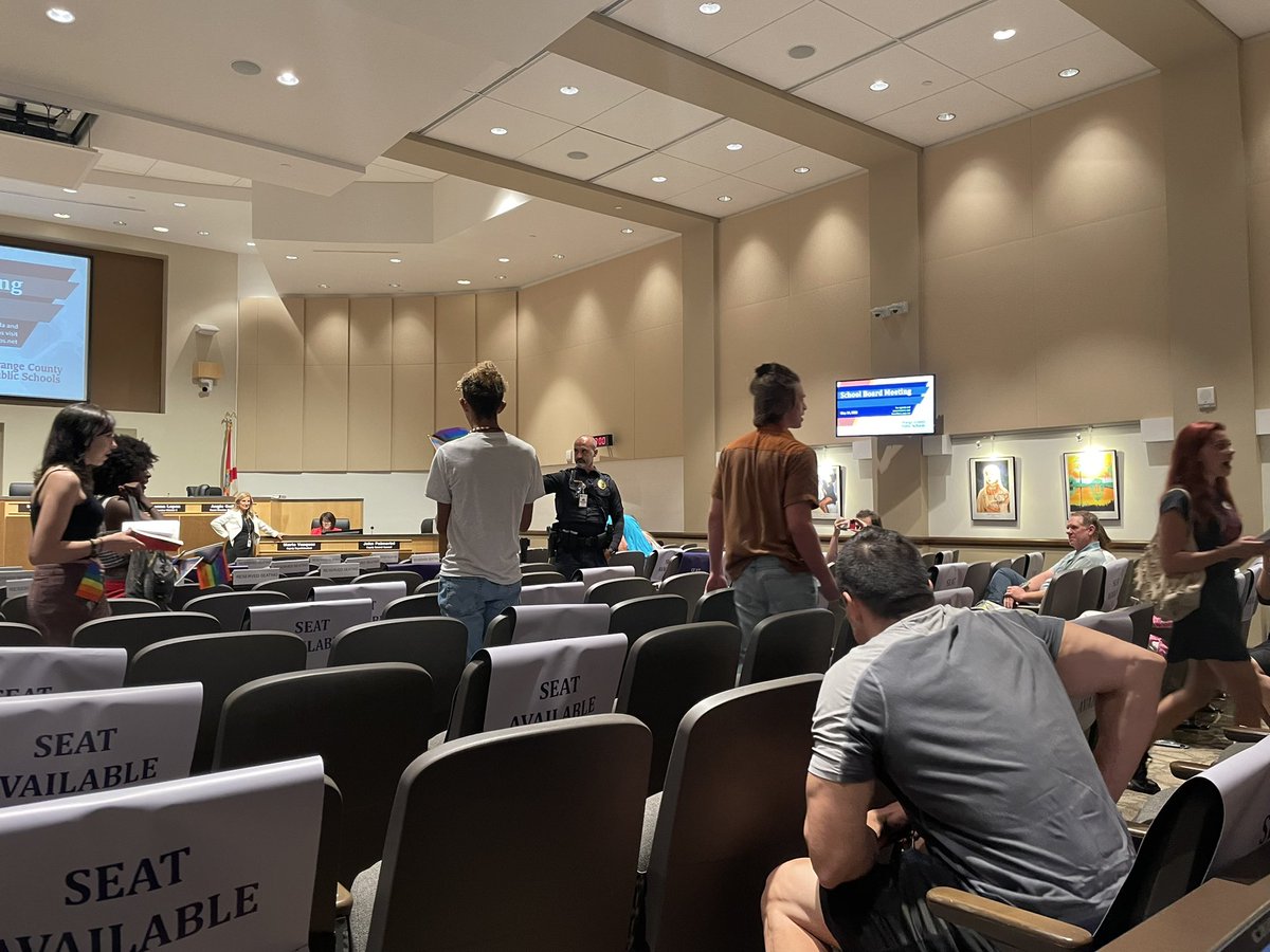 Students are escorted out of the Orange County School Board meeting after they began singing in protest of the district potentially banning LGBTQ books.