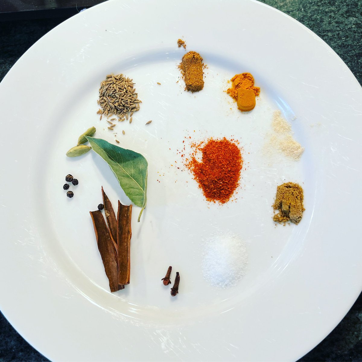 Mise en place for chana masala with my patients today— Clockwise from the top: garam masala, turmeric, asafoetida, ground cumin, salt, cloves, cinnamon stick, green cardamom, bay leaf, whole cumin seeds, red chili powder (rashampatti), center. #culinarymedicine #indianfood