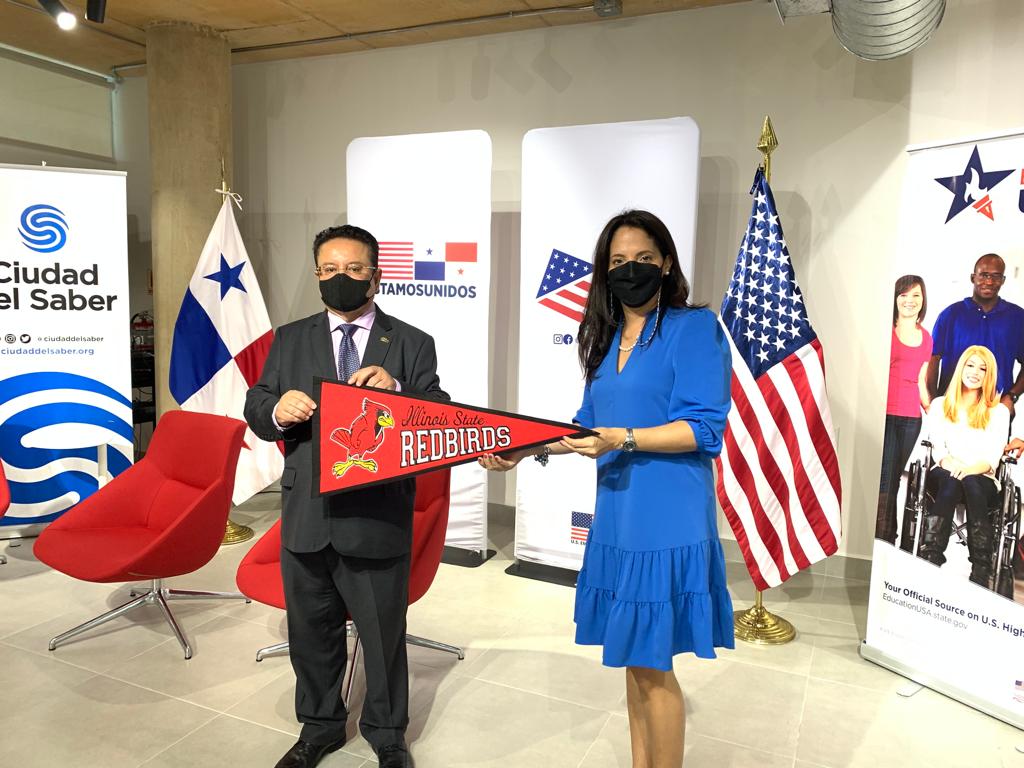 Oscar Leon, Rector de Quality Leadership University (QLU) entrega el banderín de Illinois State University (ISU) a Gradys Bernett, Directora de EducationUSA Panama en la inauguración de las instalaciones del Panama American Center, acto en el que participó Ethan Rosenzweig.