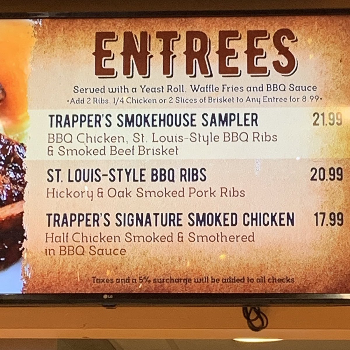 BGWFans's tweet photo. Just how scummy is this new surcharge? An anonymous friend of the site sent us this photo from Trapper's Smokehouse. The new disclaimer is in small, dark text on a darkened background on a digital menu screen where the prices could have been changed just as quickly. Disguising. https://t.co/u4uxYmdOPV