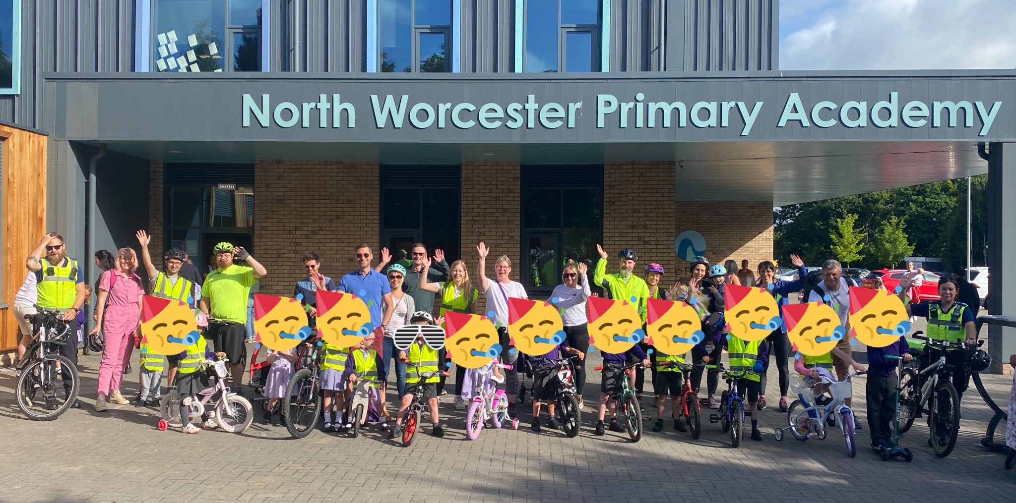 Group of children and grown ups stood outside a school on their bikes