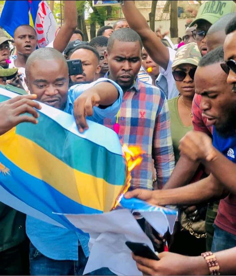rwandaiskilling's tweet photo. #RDC : Manifestation ce lundi  des Congolais  devant l’ambassade du Rwanda à Kinshasa. Ils exigent la fin totale des relations diplomatiques avec le pays de Paul kagame , le drapeau du Rwanda brûlé par les manifestants.

#RwandaIsKiling https://t.co/hwFBtycRa2