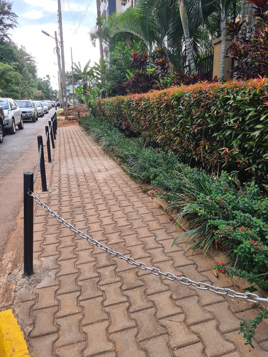 DDPozhidaev's tweet photo. Fellow Kampalans, can someone explain what's the point of constructing sidewalks &amp; then making them inaccessible to the users they are designed for, ie pedestrians? Why would someone put chains around a sidewalk? https://t.co/LBe98gLrdw