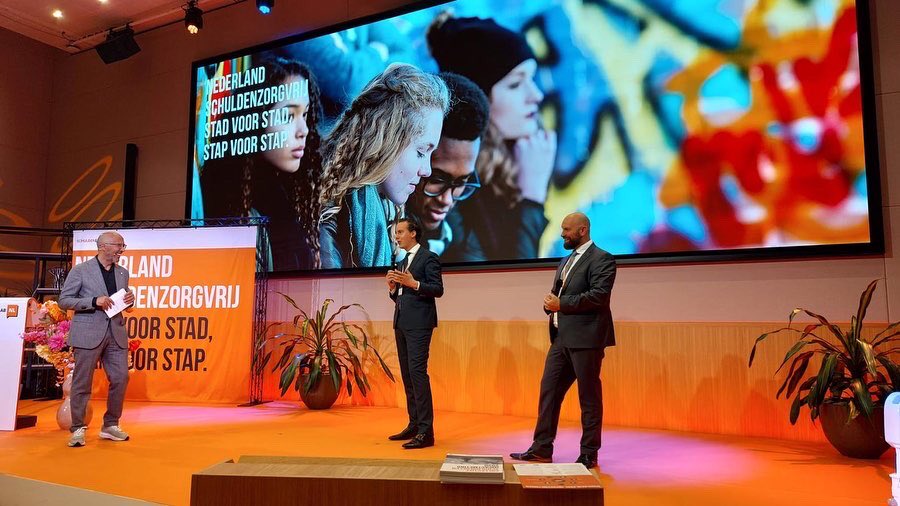 arjenmaathuis's tweet photo. Vandaag samen met collega @boazadank van #Breda mogen spreken op bijeenkomst van het @schuldenlab. In (digitale) aanwezigheid van HM de Koningin &amp; minister Schouten. Net zoals Breda is #Almelo een koplopergemeente, waar de Majesteit blijkens haar toespraak trots op is! https://t.co/lvLzeqYX2X